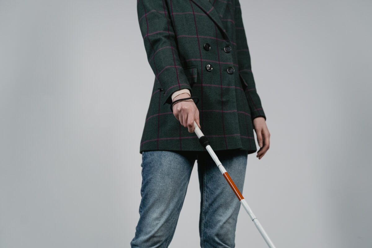 Foto que muestra torso de persona ciega usuaria de bastón con vestimenta formal